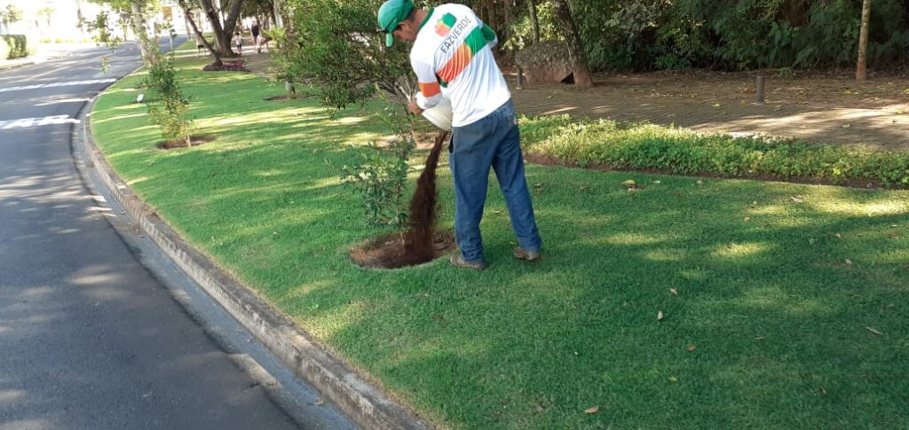 Homem uniformizado aplicando composto orgânico sobre 